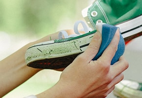 Hand cleaning a sports shoe with Scotch-Brite sponge